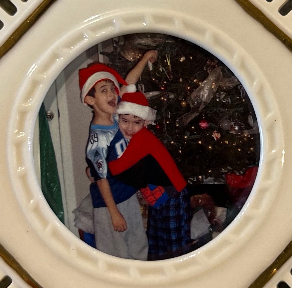 Drew Fillinger hugging Nicholas Fillinger as they hang ornaments on the tree
