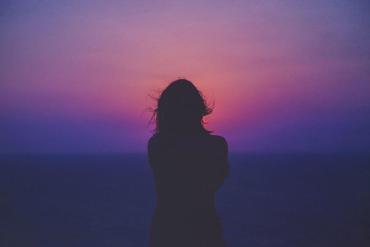 woman watching sunset contemplating an unwelcome realization.